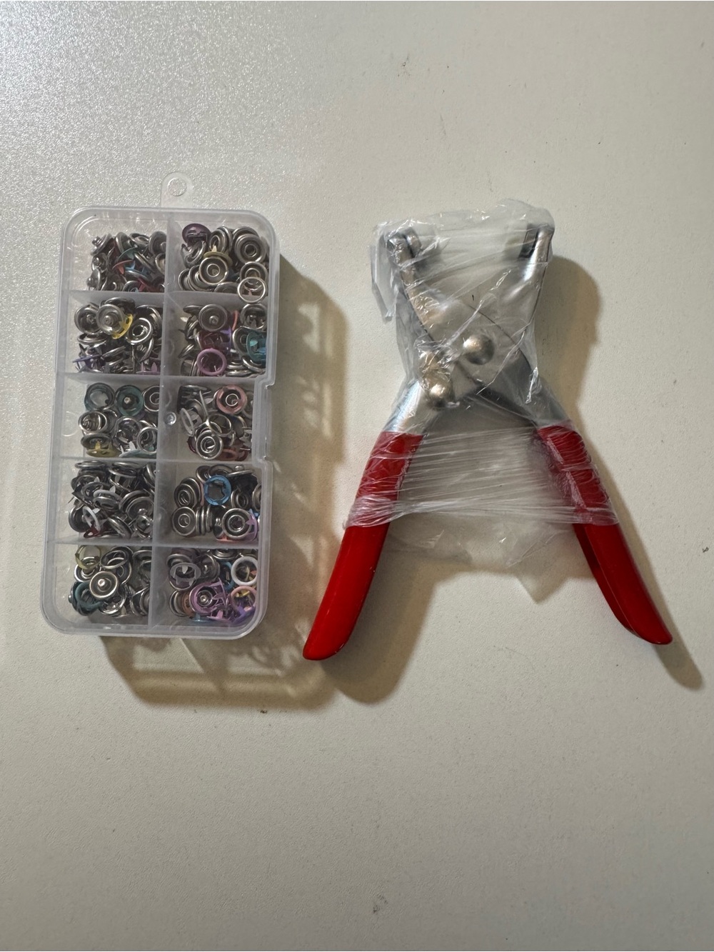 Handheld Snap Pliers with Red Handles and Assorted Metal Snap Fasteners